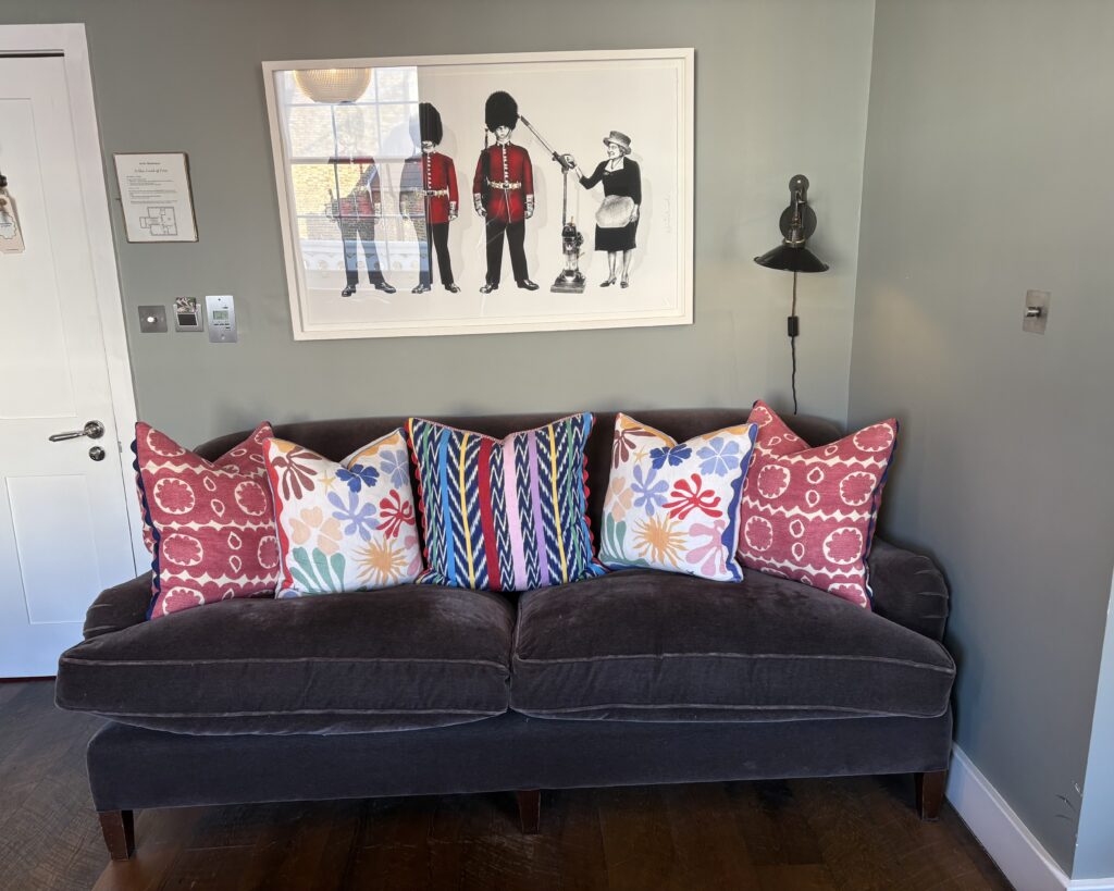 Eclectic living room with dark velvet sofa, mixed pattern cushions and Queen's Guard print — Artists Residence London Club Suite