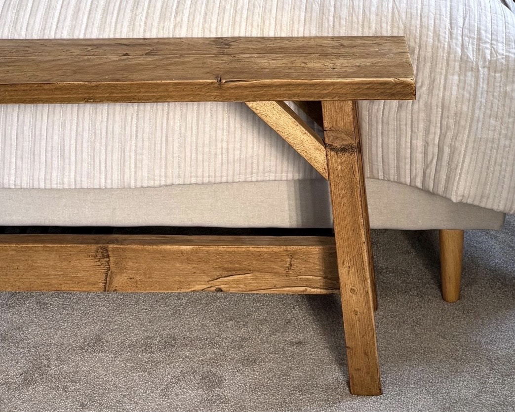 Rustic wooden end-of-bed bench in a beige bedroom