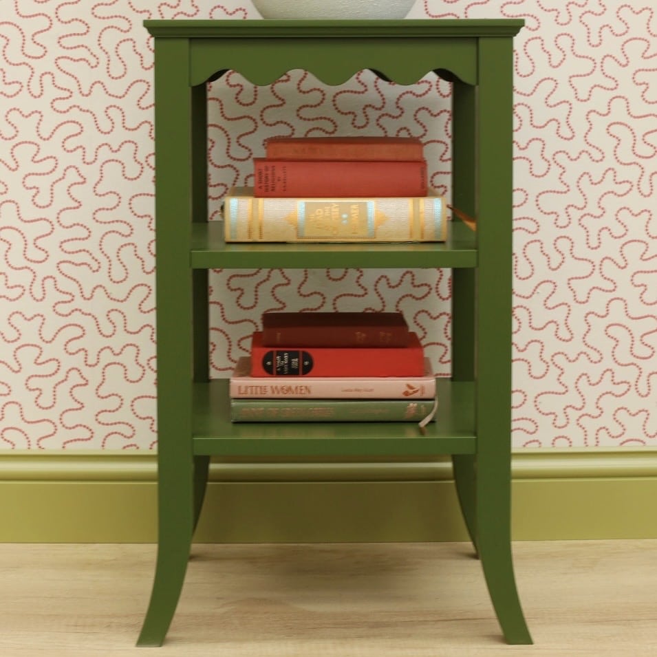 Green scalloped bedside table with a wavy apron detail grounding the pink and green bedroom
