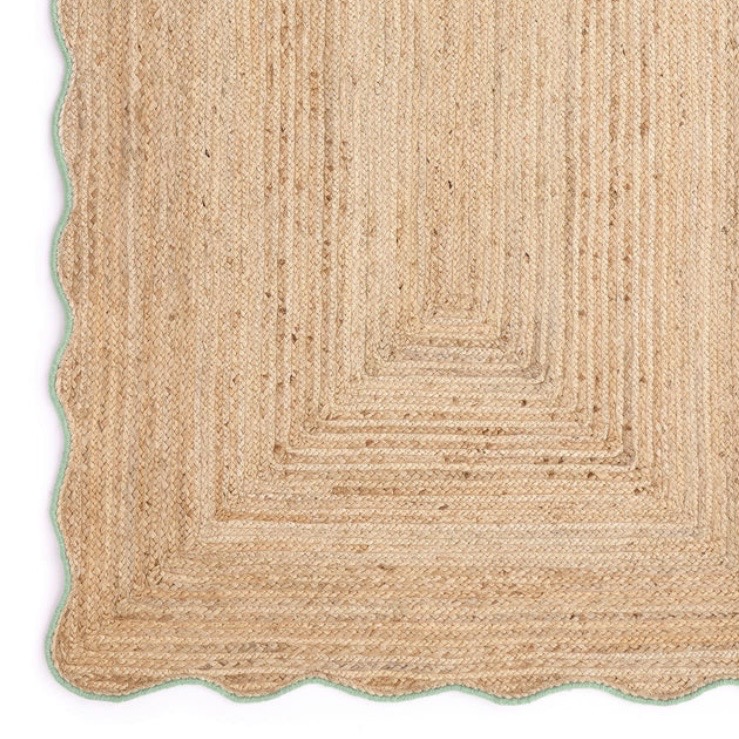 Natural jute rug with a green scalloped edge setting off the pink and green bedroom