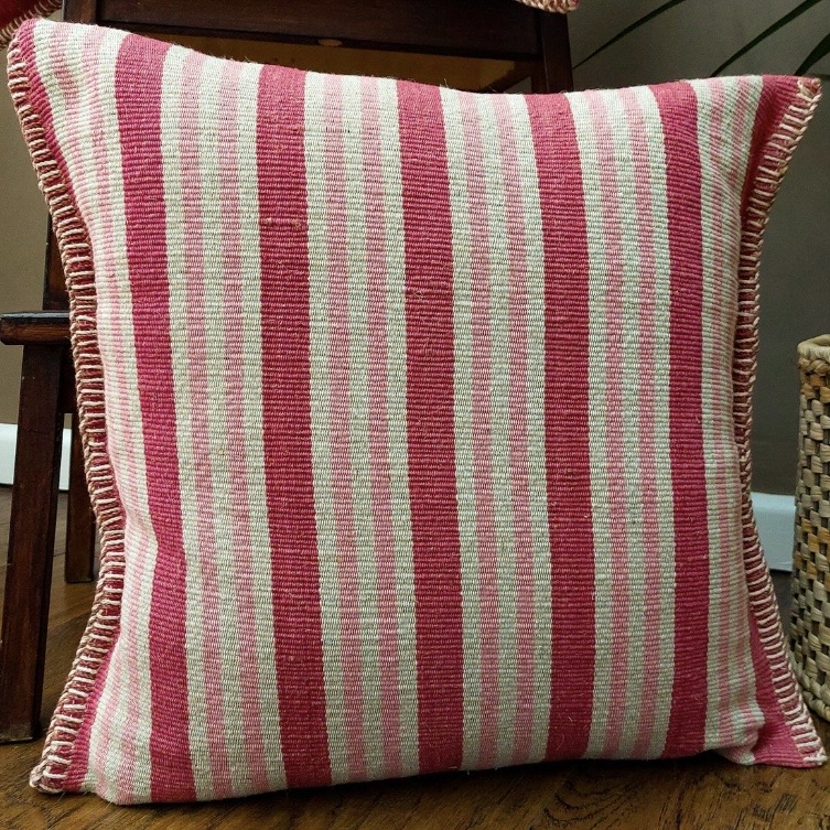 Pink striped cushion cover with woven texture in a pink and green bedroom