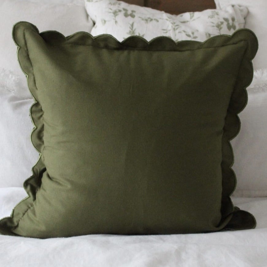 Khaki green scalloped edge cushion cover in a pink and green bedroom