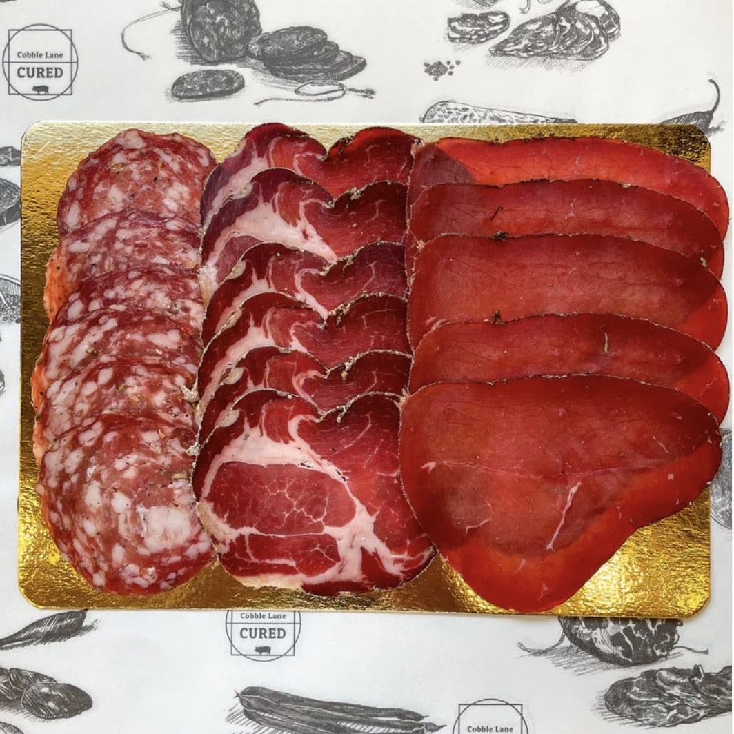 Cobble Lane Cured charcuterie platter with fennel salami, coppa and bresaola on gold paper – British artisan charcuterie from Farm Fetch