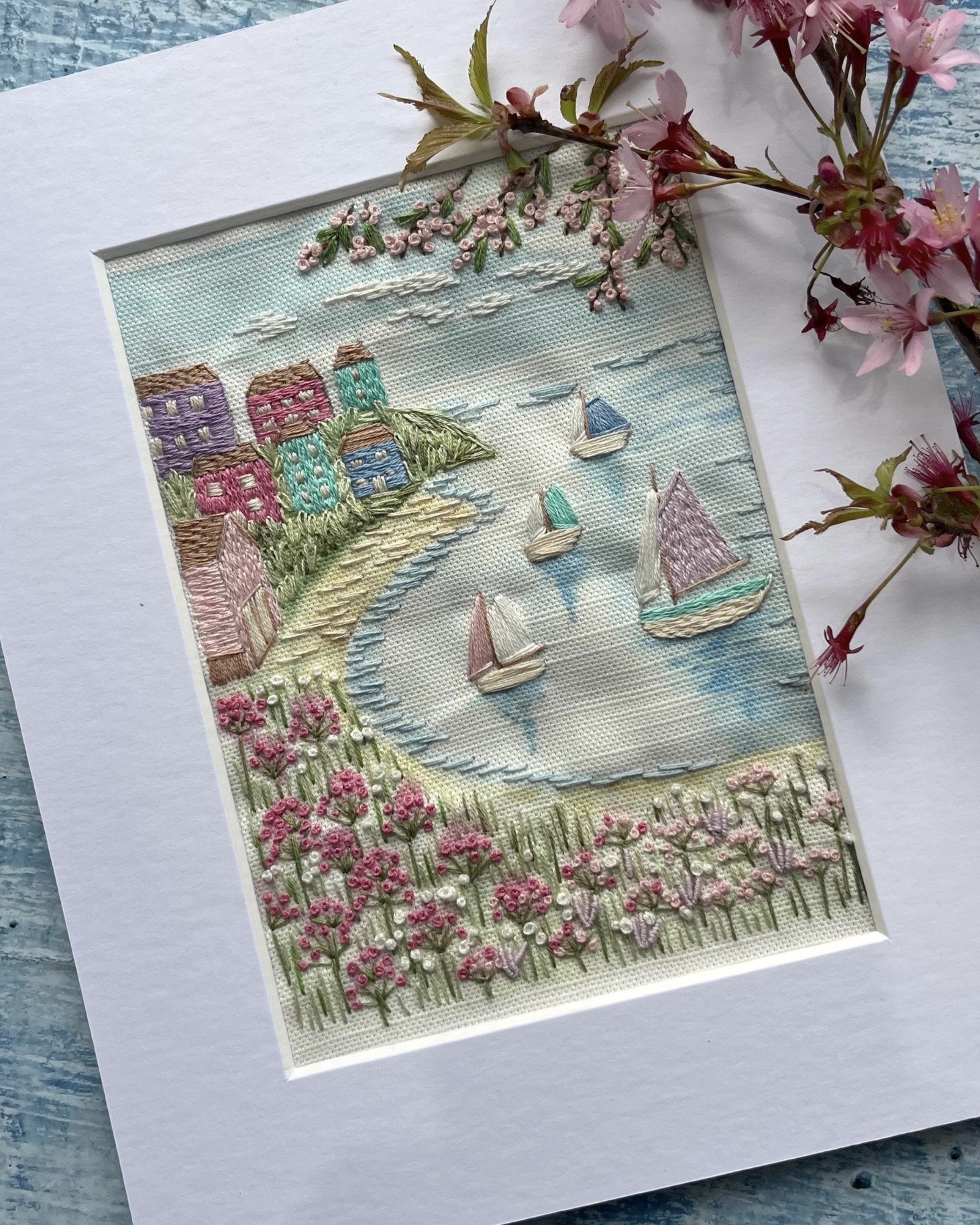 Hand embroidered coastal artwork with boats and cottages for cottage bedroom decor