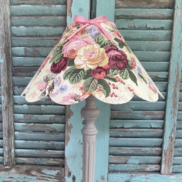 scalloped floral lampshade with rose print on vintage style lamp base against rustic blue shutters cottage decor