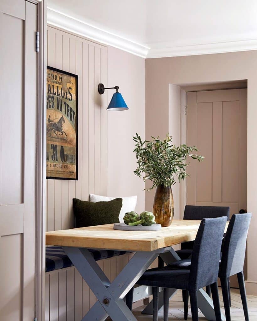 small dining room with Farrow and Ball Dead Salmon panelling, bench seating, blue wall sconce and vintage poster art