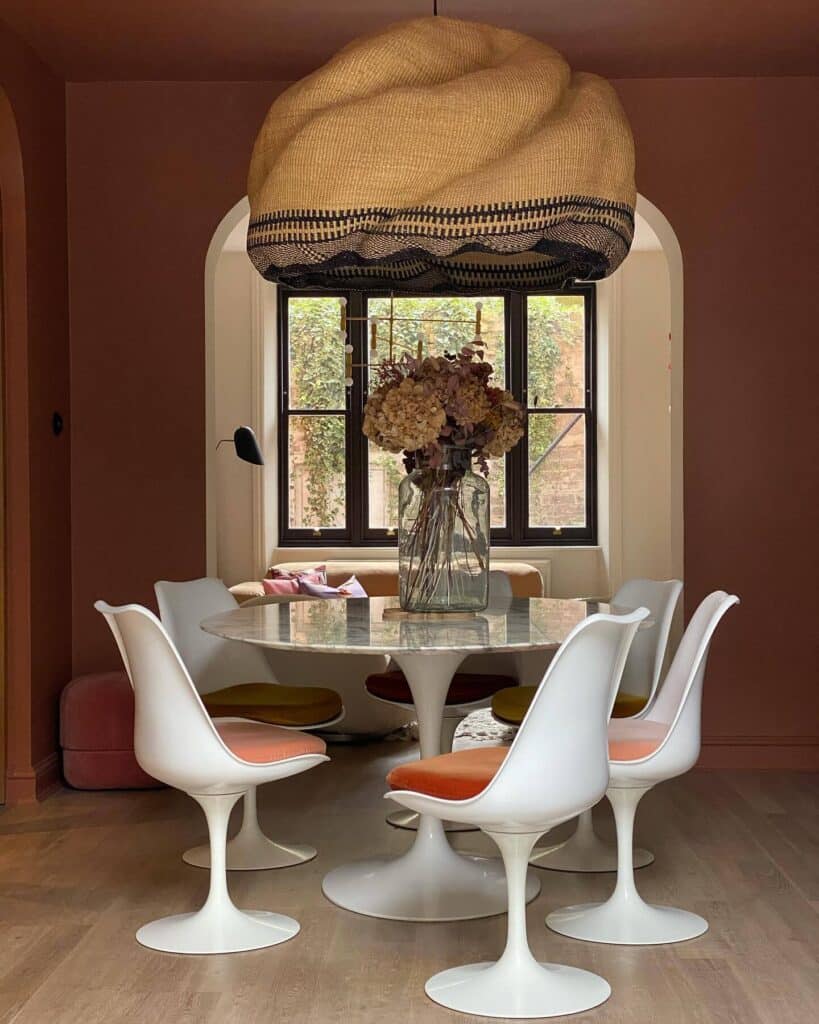 warm terracotta dining room in Farrow and Ball Fox Red with Tulip chairs and sculptural woven pendant light