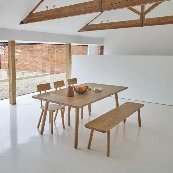 Japandi dining room with Another Country solid oak dining table and Bench One in a barn conversion with white walls and exposed timber beams