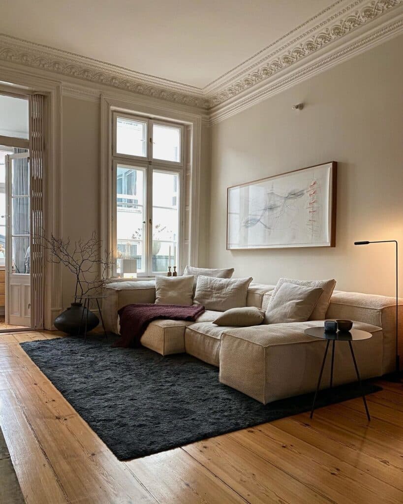 Japandi living room with large linen corner sofa, dark charcoal rug, slim black floor lamp and abstract framed art painted in Farrow and Ball Slipper Satin