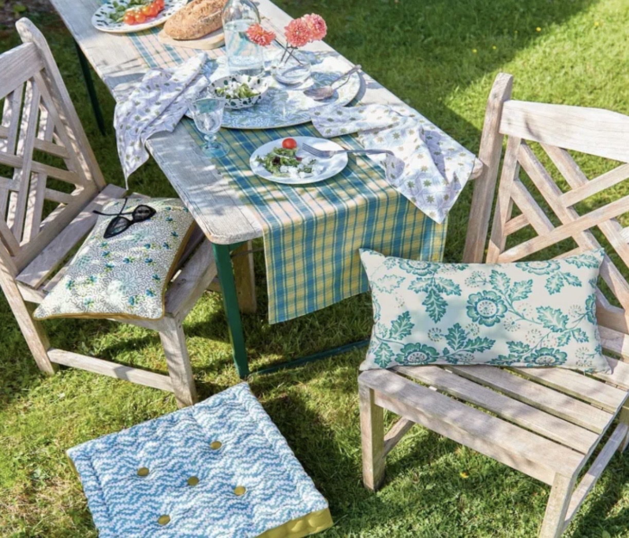 Garden dining table styled with Land and Shore teal block print outdoor cushions, check table runner and coordinating napkins