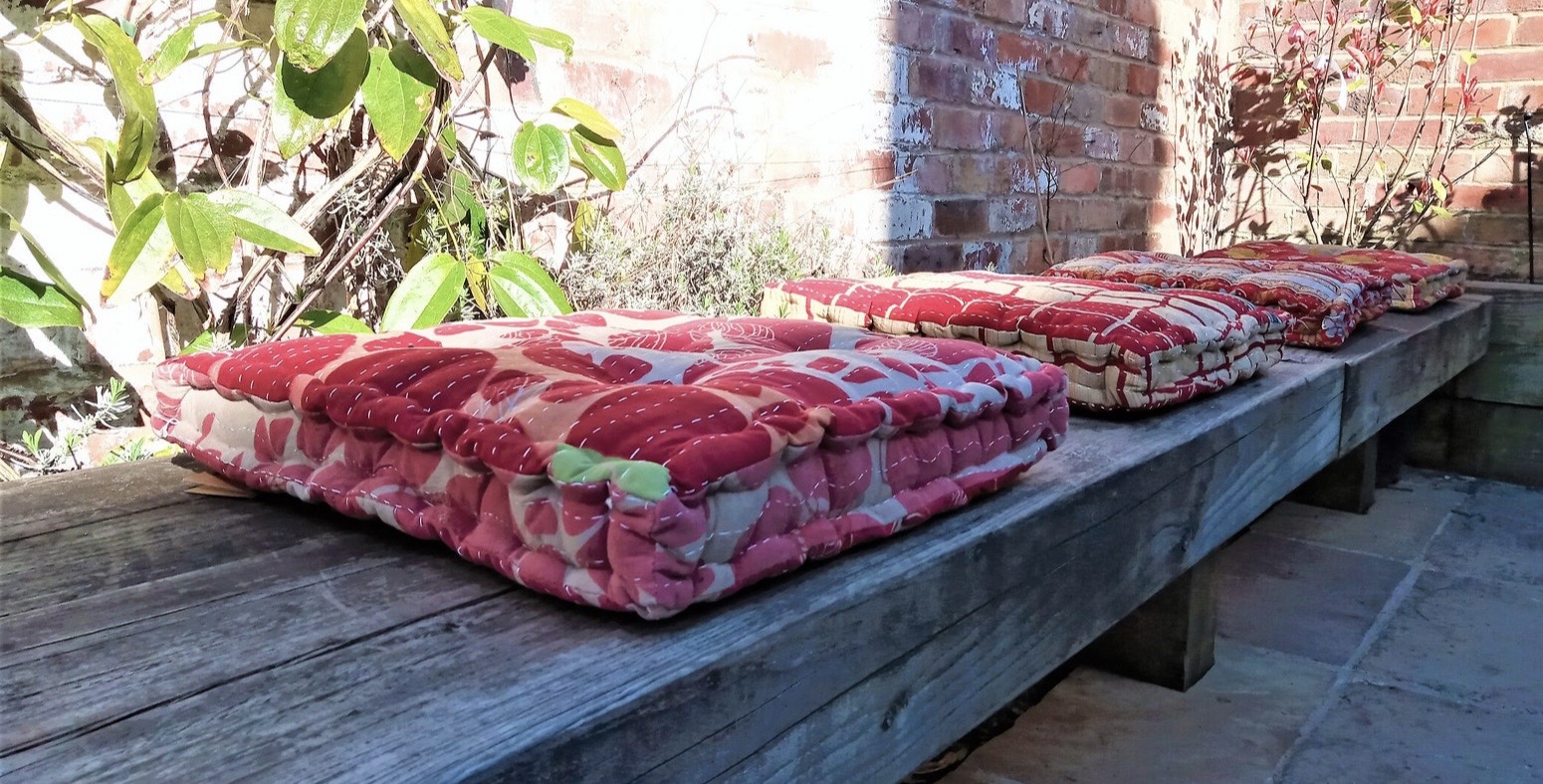 Kantha stitched outdoor floor cushions in upcycled vintage sari fabric in deep red and cream on weathered wooden garden bench