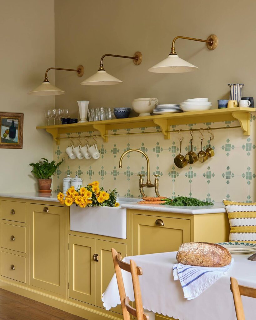 Warm yellow kitchen cabinets painted in Farrow & Ball Sudbury Yellow with brass taps, patterned tiles and open shelving