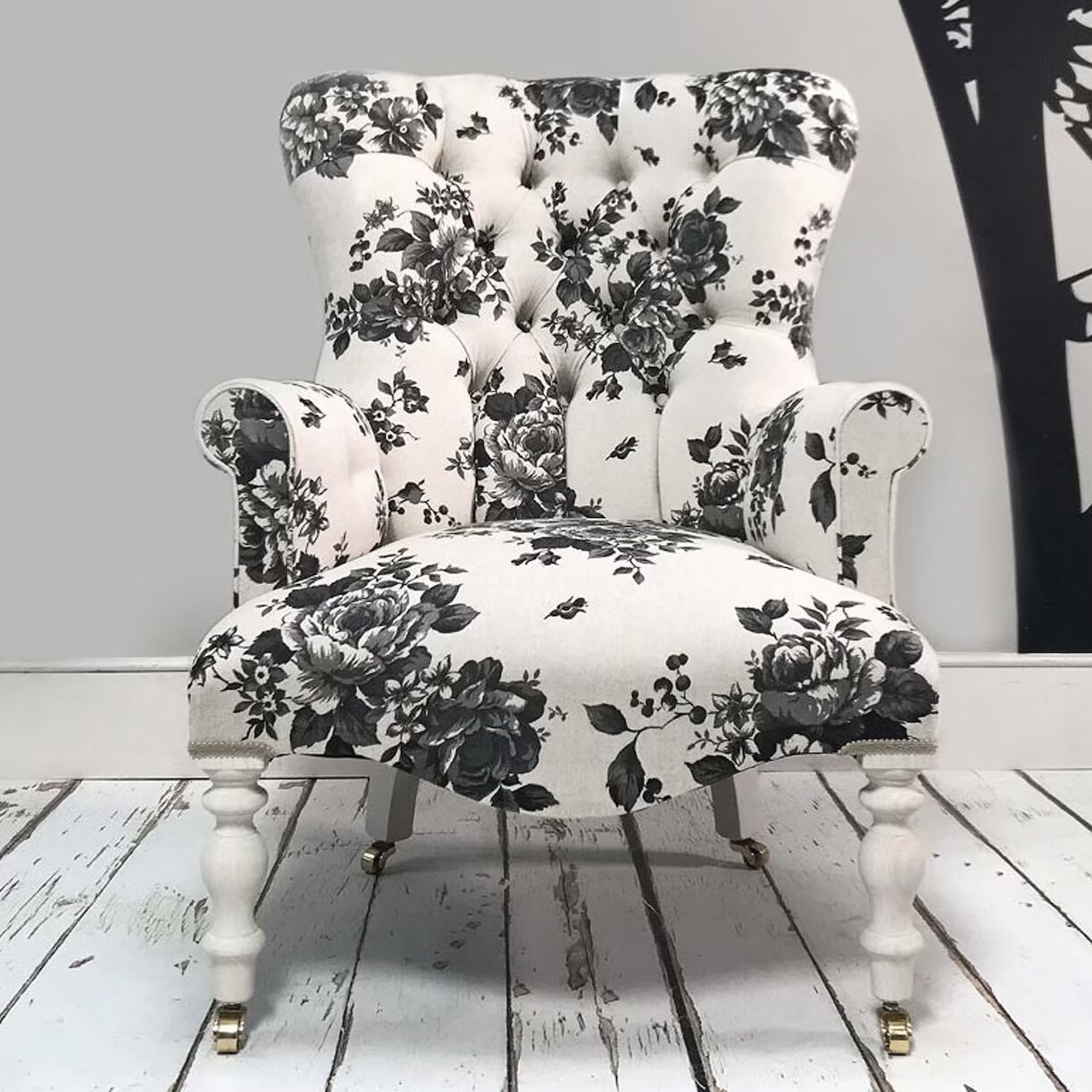 Georgia Rose accent chair upholstered in a black and cream floral print with button tufting and turned white wooden legs