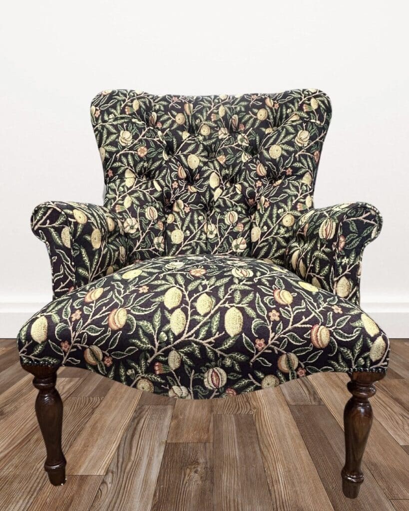 William Morris style floral accent chair upholstered in dark botanical fabric with turned wooden legs.