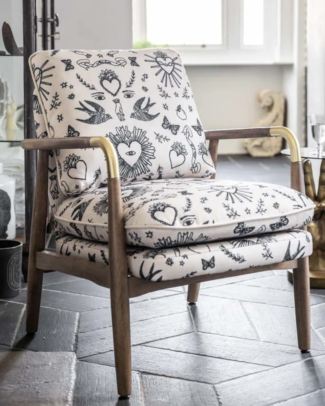 Cream accent chair upholstered in a black hearts and flowers print with a solid oak frame.