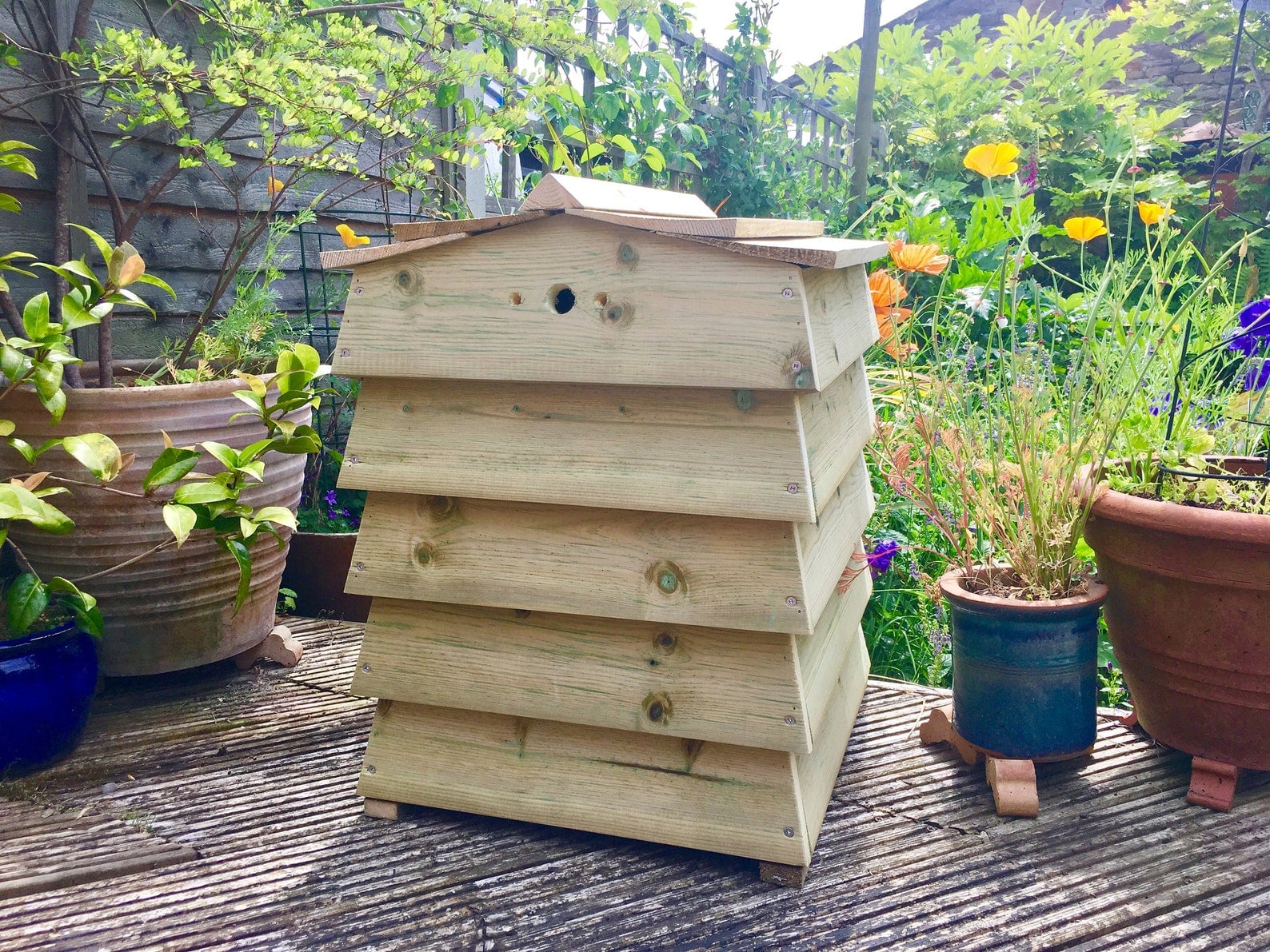Stackable beehive style compost bin in a garden setting