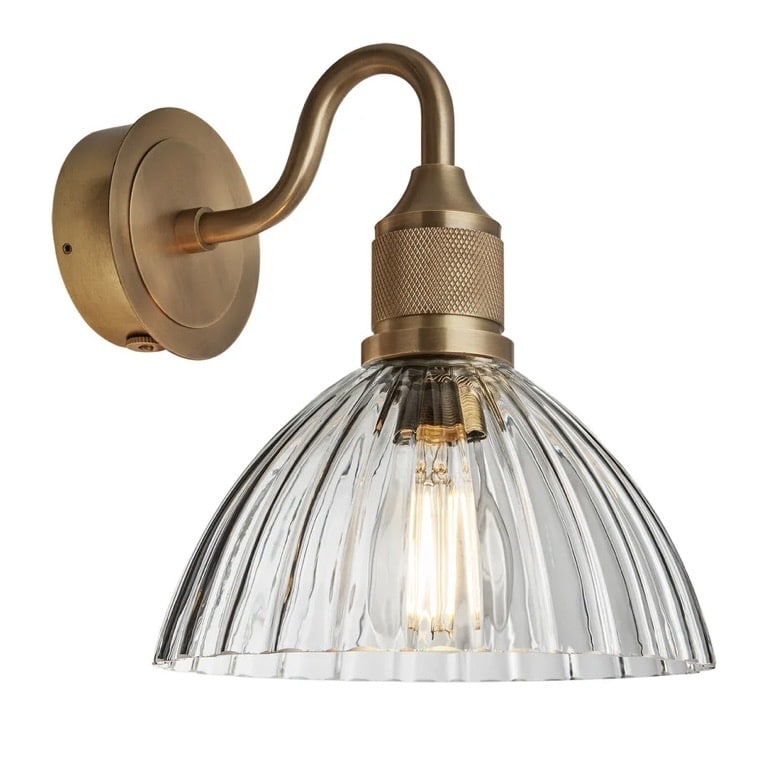 Prismatic glass wall light with swan arm in satin brass adds vintage charm to a neutral bathroom