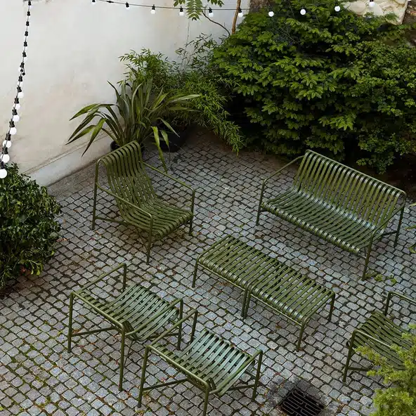 HAY Palissade Garden Dining Bench in olive green on a courtyard patio
