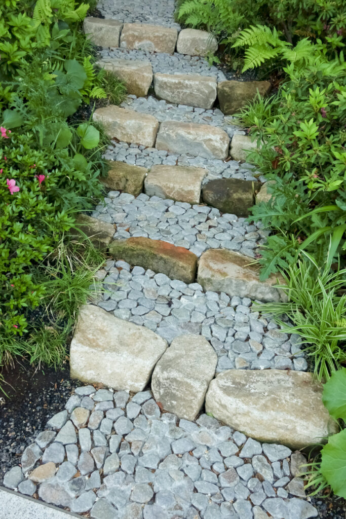 Stacked stone steps backfilled with pebble on a sloped garden path, garden path ideas
