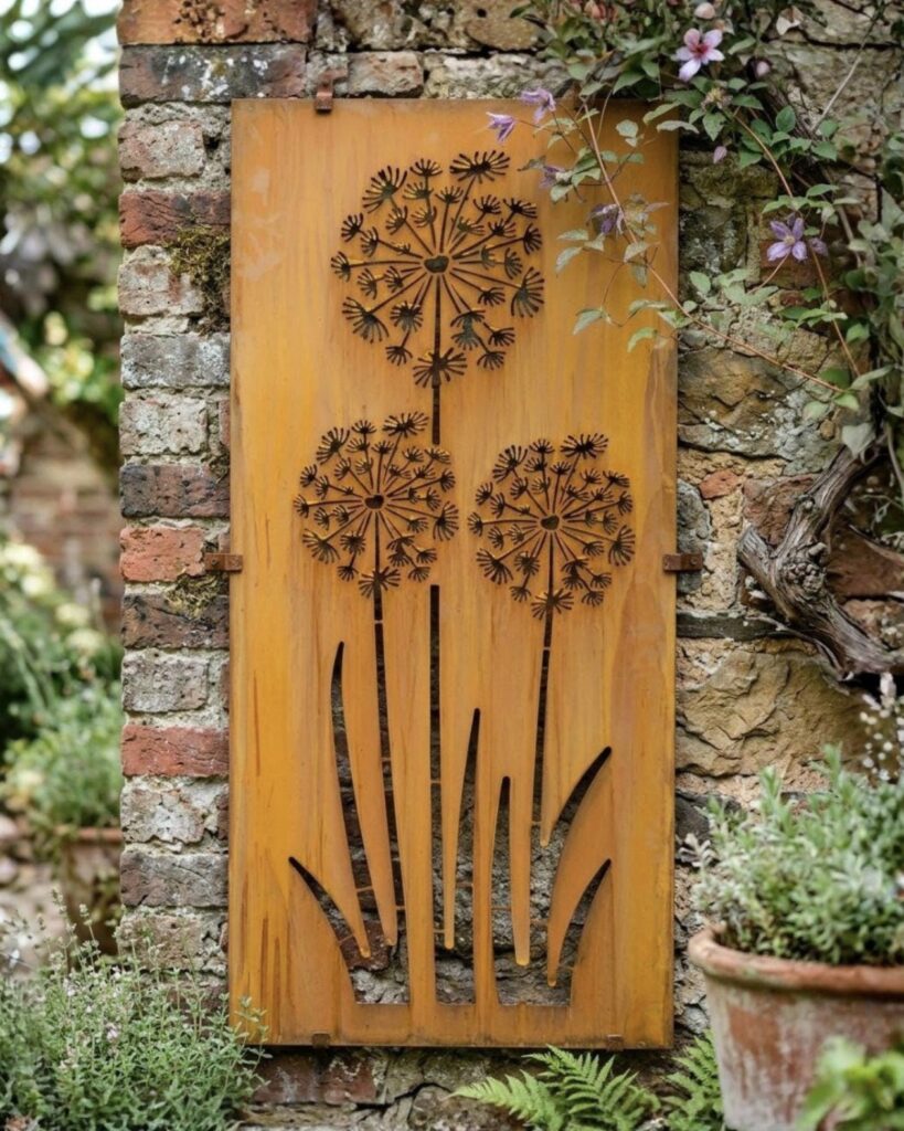 Rusted metal dandelion wall art panel mounted on a brick garden wall