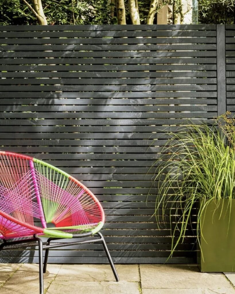 Slatted timber garden fence painted in dark grey with green planter