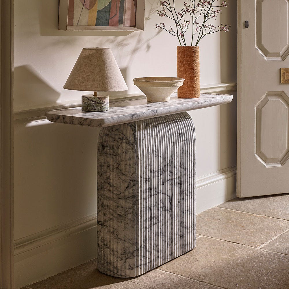 Fluted marble console table with lamp, bowl and vase styled in a period hallway alcove