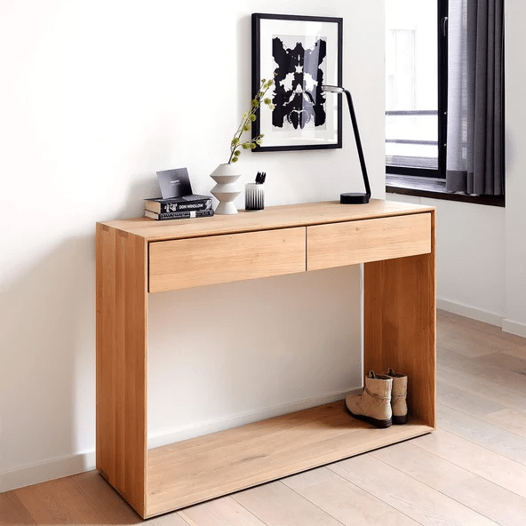 Oak console table with open shelf holding boots, styled with a lamp and framed print in a hallway