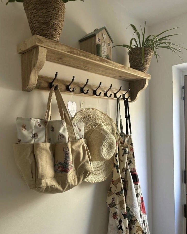 Handmade reclaimed scaffold board coat rack with shelf, hooks holding bags and a hat in an entryway