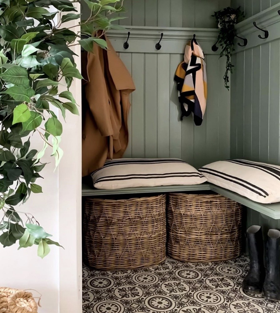Green panelled boot nook with wicker storage baskets and coat hooks
