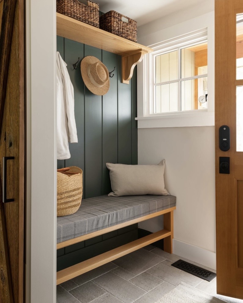 Dark blue-green panelled mudroom nook with bench seating and coat hooks