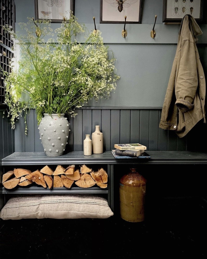 Dusty blue panelled entrance hall with built-in firewood storage