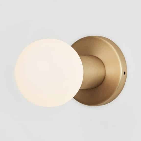 Tala Lochan graphite bathroom wall light above a concrete vanity with arched mirror and white ribbed tiling