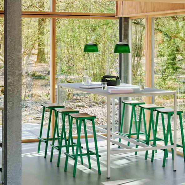Six green backless breakfast bar stools with ash seats at a long poseur table
