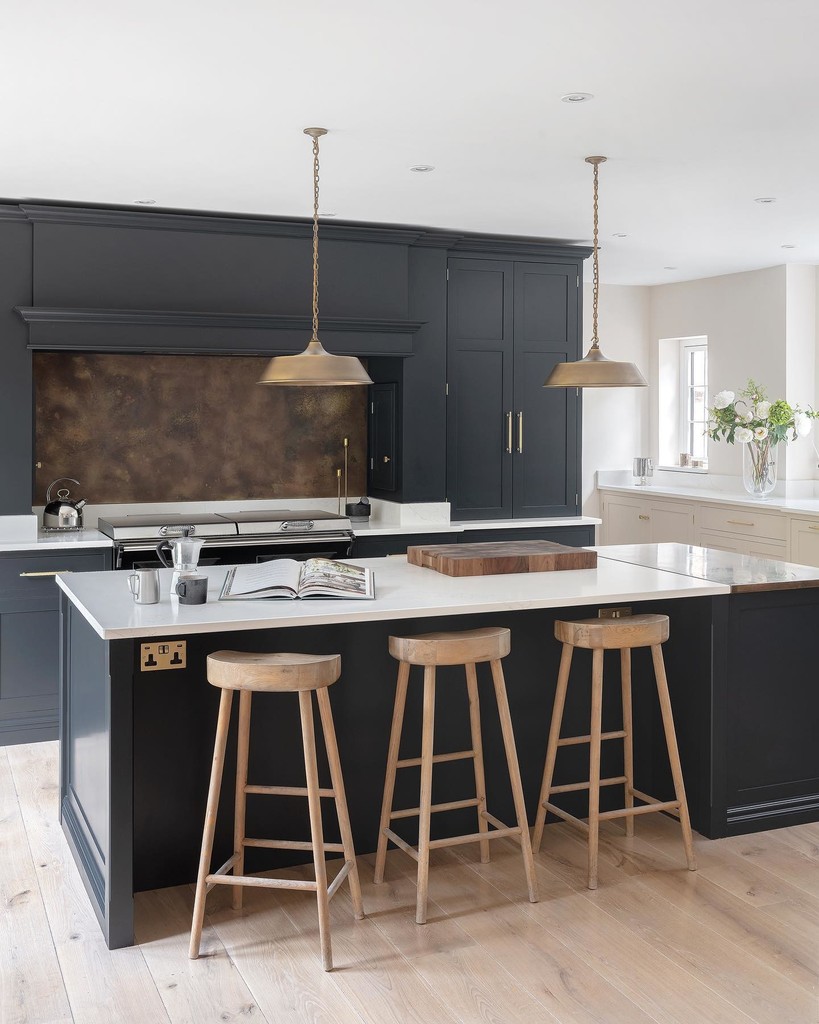 Three backless oak breakfast bar stools spaced evenly along a dark island in an Off-Black kitchen