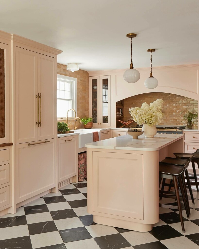Dark timber breakfast bar stools at a pale pink kitchen island with checkerboard flooring