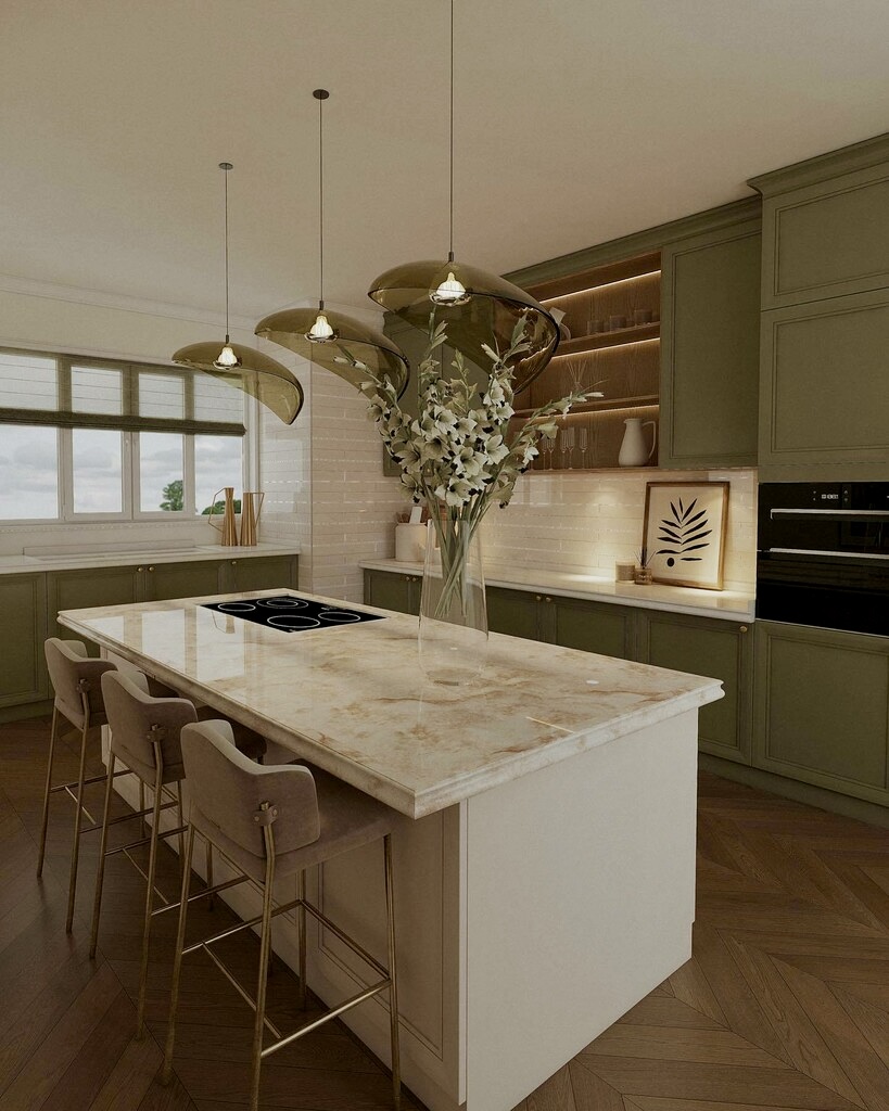 Three taupe upholstered breakfast bar stools with brass legs at a marble island in an olive green kitchen