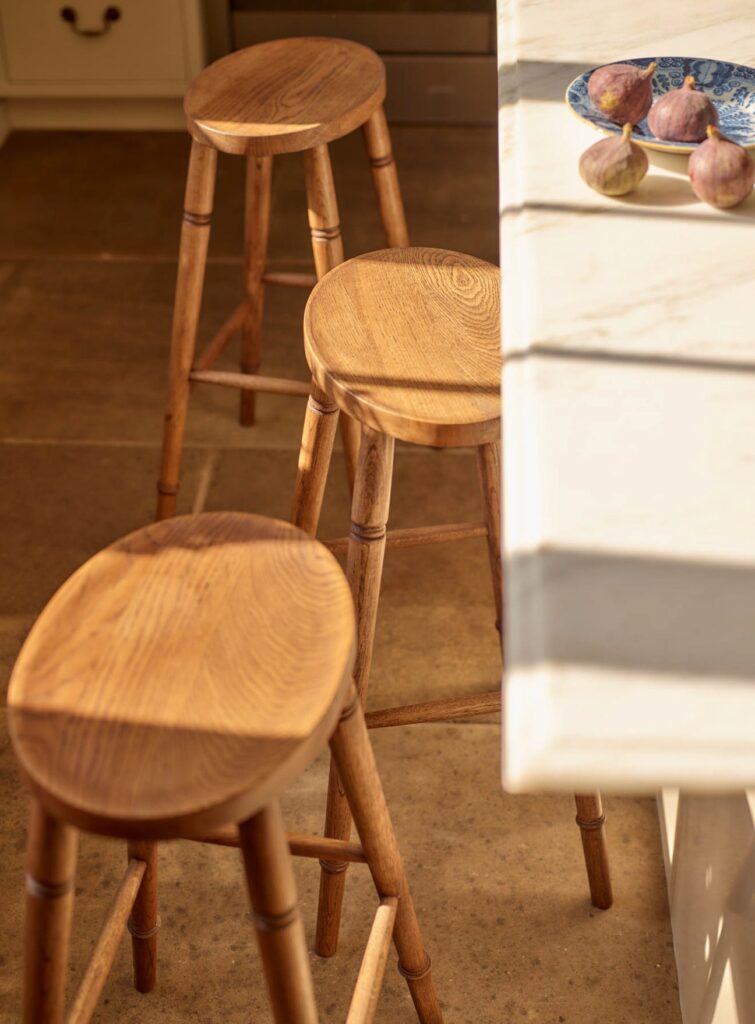 Three hand-carved oak bar stools with oval sculpted seats and turned legs