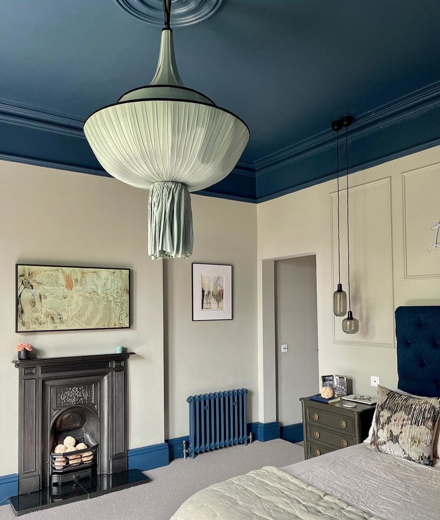 navy and grey bedroom with painted ceiling and period fireplace