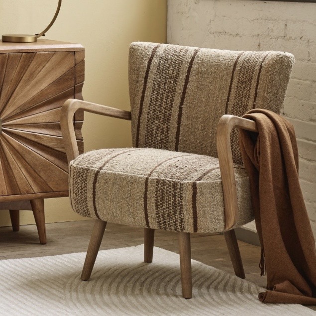 Calvin striped accent armchair in a brown and oatmeal woven rug fabric with curved oak arms, beside a sunburst sideboard