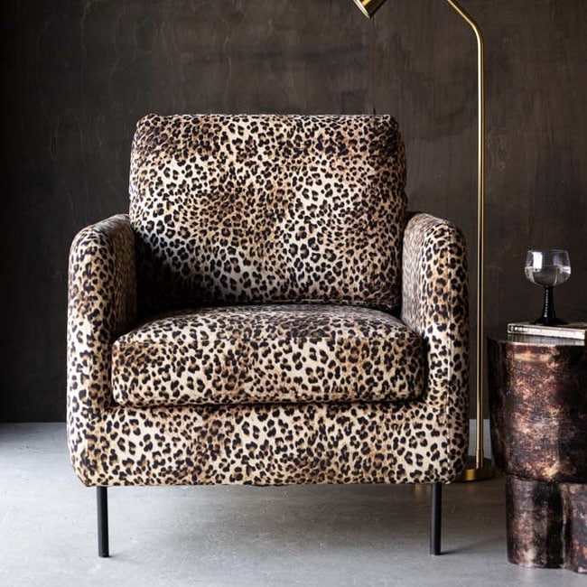 Edie leopard print accent chair in tan velvet with slim black legs, beside a brass floor lamp