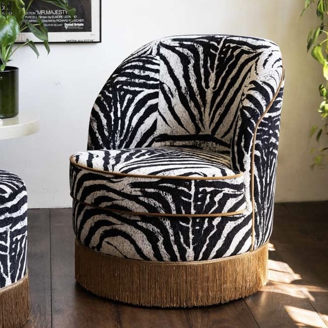 Zebra print swivel accent chair in black and white velvet with gold piping and a gold fringed base