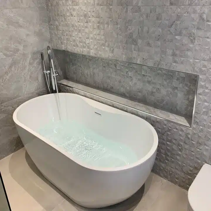 Porcelanosa sale Cubik Indic relief wall tiles behind a white freestanding bath with a recessed shelf