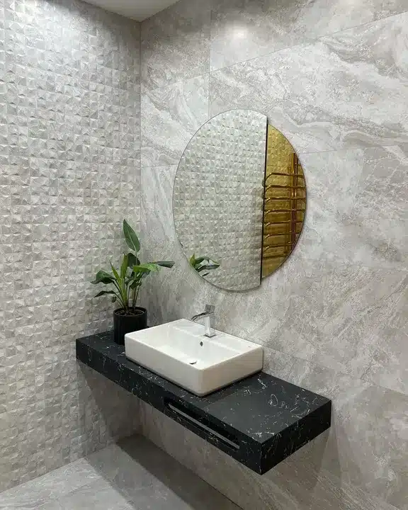 Grey Cubik Indic relief wall tiles beside a black floating vanity with a round mirror and brass towel rail