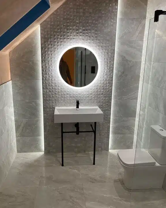 Cubik Indic relief tile feature wall behind a washstand basin with a backlit round mirror in a loft bathroom