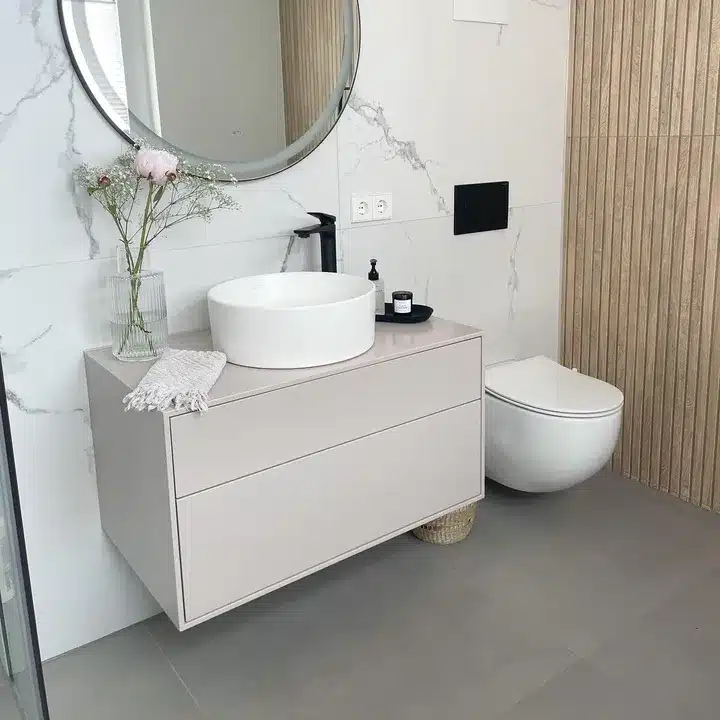 Marble-effect wall tiles beside a slatted wood-effect wall with a round vessel basin and greige vanity