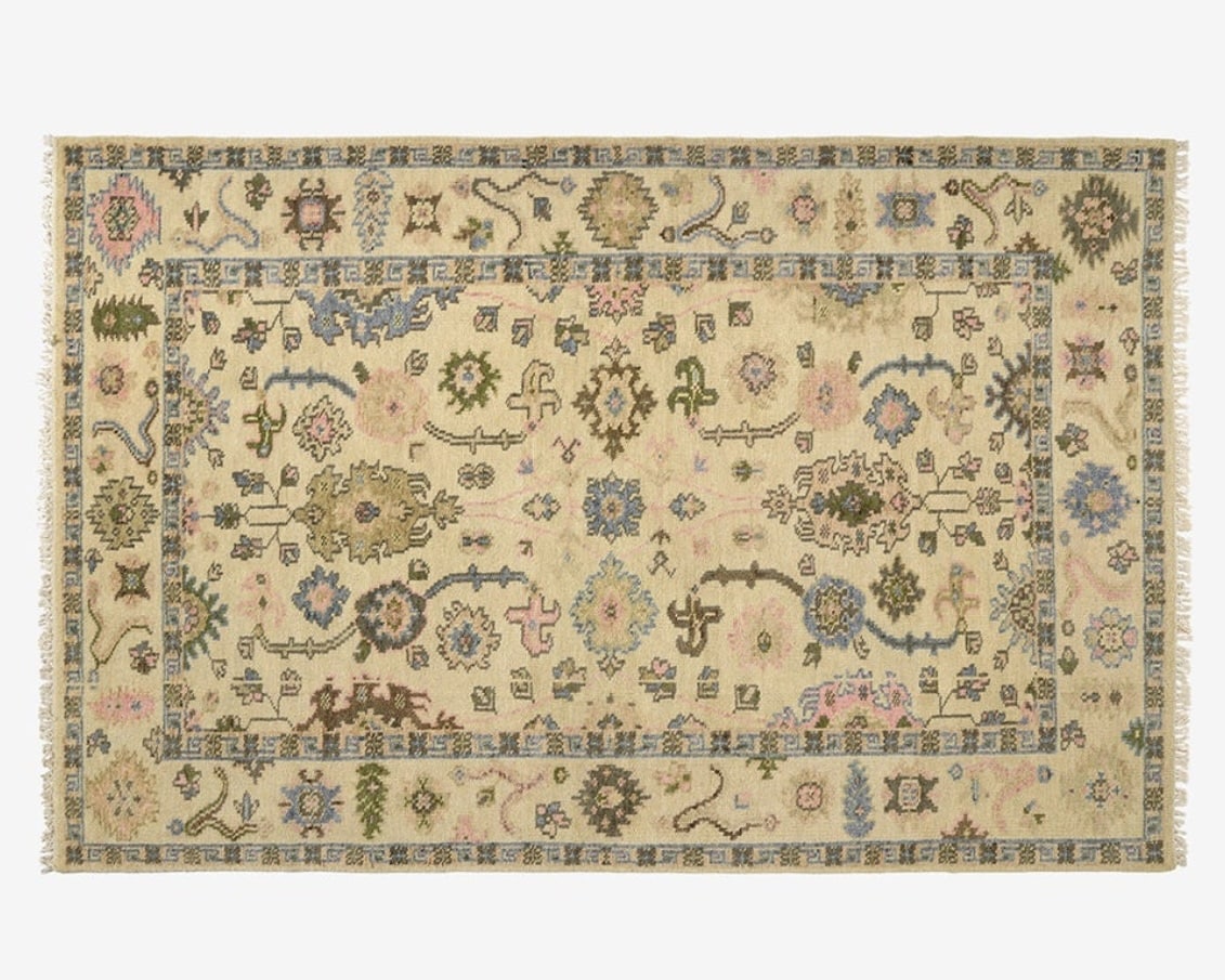 Patterned Persian rug in warm beige under a tan leather sofa