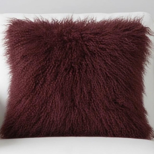 Burgundy Mongolian sheepskin cushion on a white leather armchair