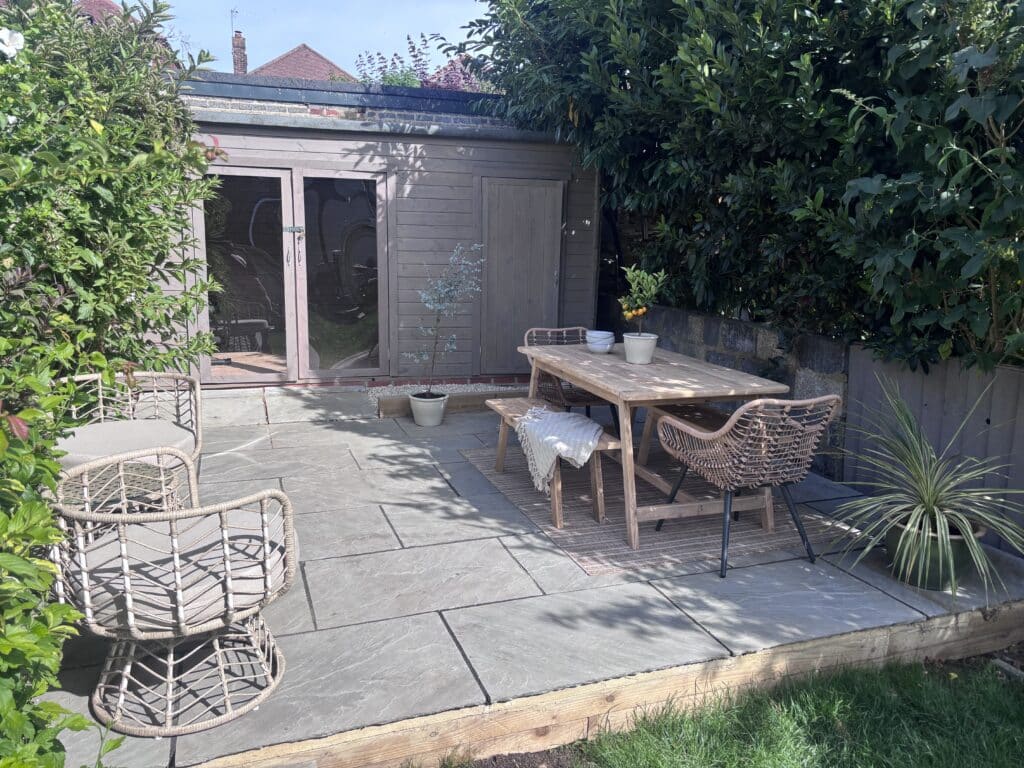 Rustic pine dining table and bench with rattan chairs on a sandstone garden patio
