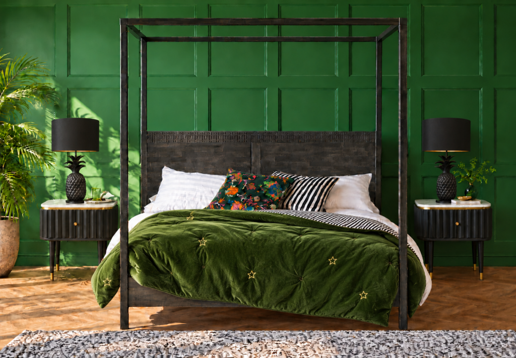 Emerald green bedroom with panelled walls, a black four-poster bed, green velvet star quilt and black pineapple table lamps