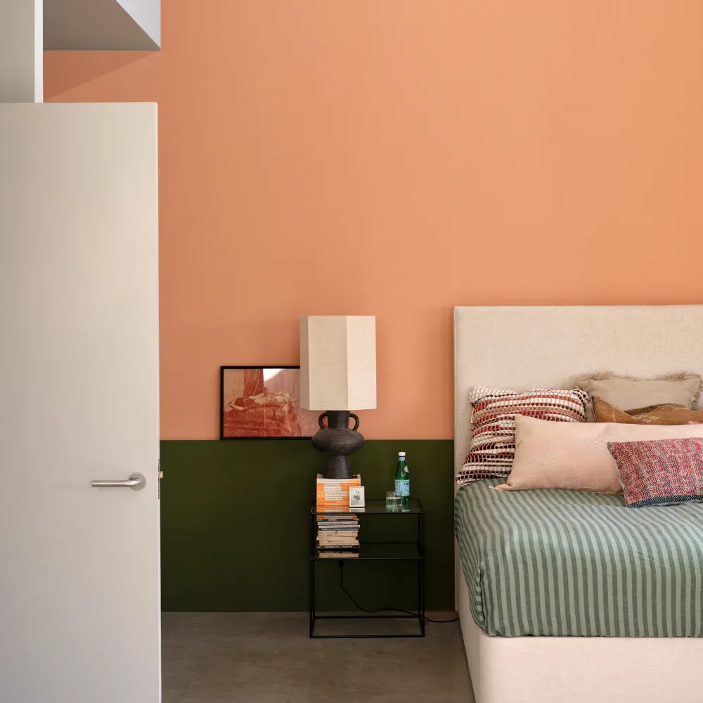 Green and orange bedroom with Farrow & Ball Naperon walls above a dark green painted band and green striped bedding